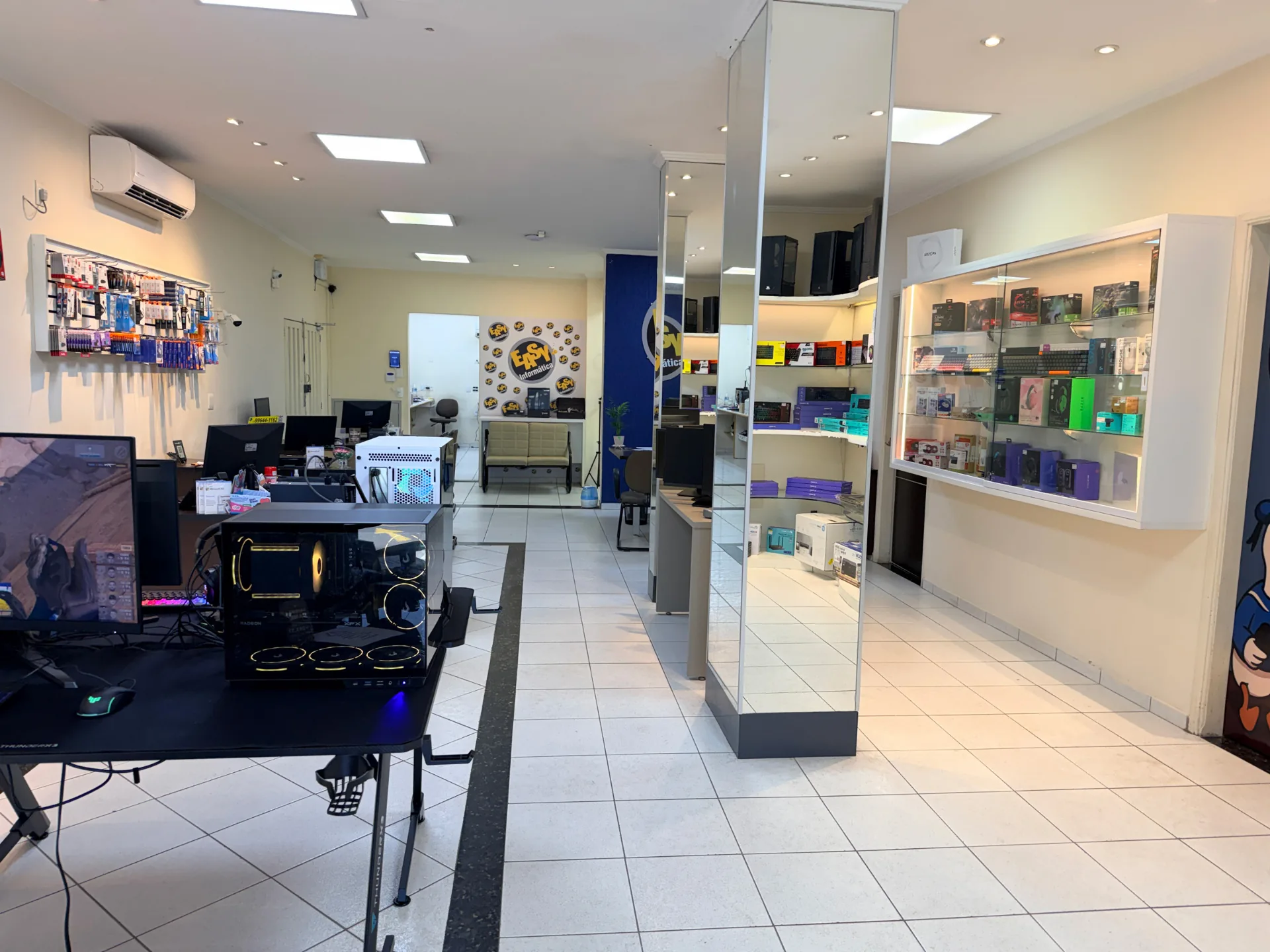 Showroom da Easy Informática com PCs gamer e área de atendimento ao fundo