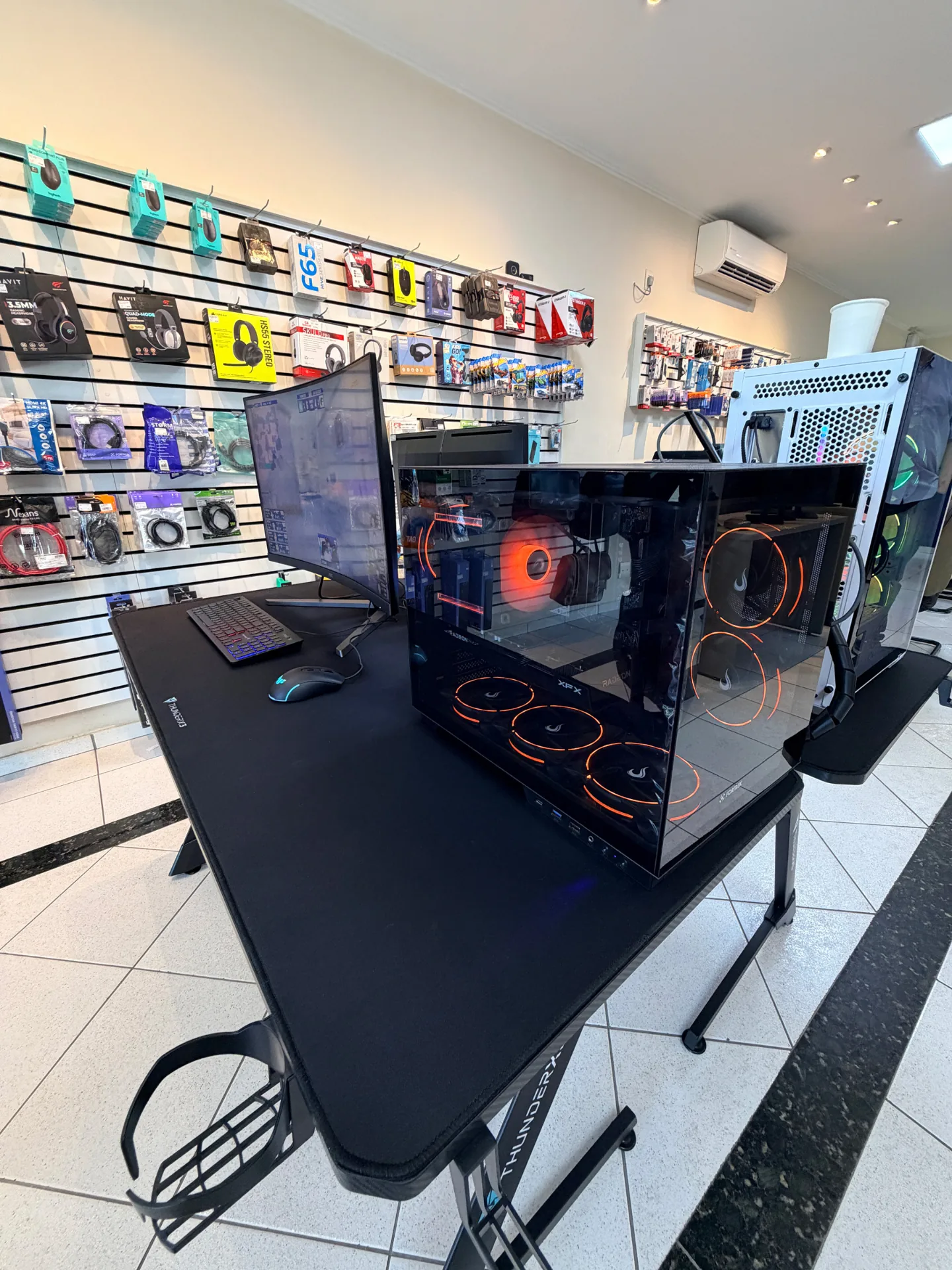 PC gamer montado em exposição com monitor curvo e periféricos